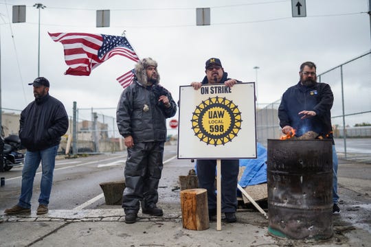 Flint Assembly electrician Mike Perez (center left) of Saginaw and (center rightly) Flint Assembly Electrician Alex Rodriguez of Detroit talk while standing on strike at the north gate of General Motors Flint Assembly on Wednesday, October 16, 2019.