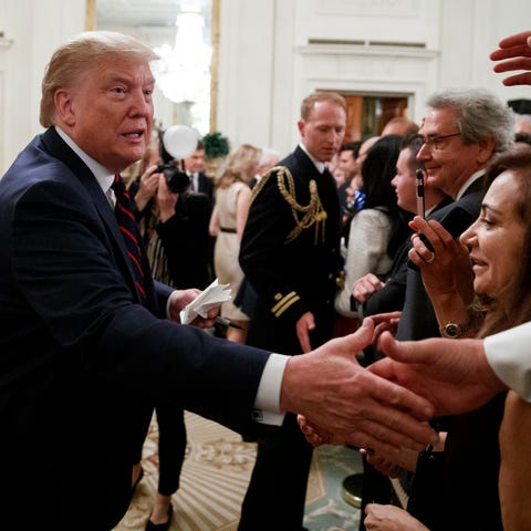 President Donald Trump reaches to shake hands duri