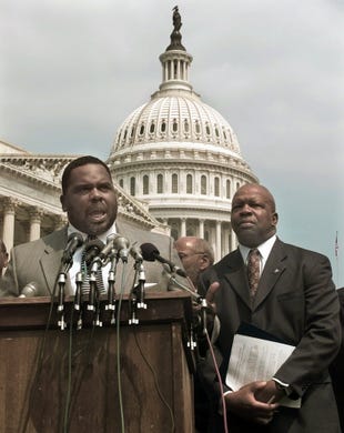 Elijah Cummings stands to the right of Rep. Albert Wynn, D-Md., as he addresses a Capitol Hill news conference on discrimination in the federal workforce on July 7, 1997.