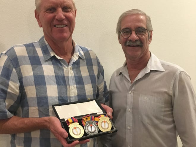 Jim McConica, left, holds up replica medals to commemorate his swimming success at the 1971 Pan-American games with friend and fellow swimmer Glenn Gruber. McConica's original medals were lost in the Thomas Fire, and Gruber researched and paid to make new ones.