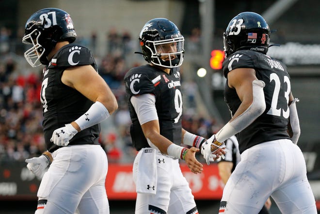 Cincinnati Bearcats quarterback Desmond Ridder (9) walks off after a touchdown run by running back Gerrid Doaks (23) in the fourth quarter of the NCAA American Athletic Conference game between the Cincinnati Bearcats and the Tulsa Golden Hurricane at Nippert Stadium in Cincinnati on Saturday, Oct. 19, 2019. The Bearcats became bowl eligible , improving to 6-1, with a 24-13 win at home.