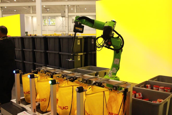 Robot FANUC, yang dibuat untuk bekerja dengan aman dengan manusia, memasukkan makanan ke dalam tas untuk Berkah amal dalam program Ransel.