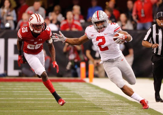 Ohio State running back J.K. Dobbins   attempts to stay in bounds as he is chased by Wisconsin cornerback Derrick Tindal during the Big Ten championship game in 2017.