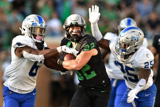 North Texas wide receiver Michael Lawrence (32) carries the ball after a catch, while being defended by Middle Tennessee linebacker Khalil Brooks (6) and defensive back Desmond Anderson (25) during the second half Saturday, Oct. 19, 2019, in Denton.