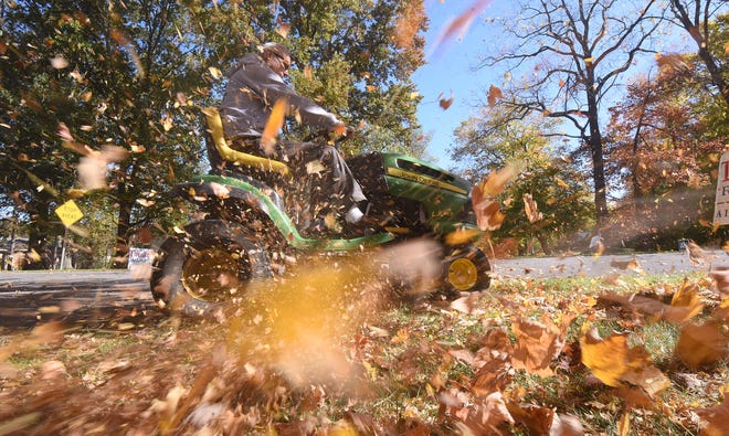 Ted Sazdanoff uses his mower to blow leaves Wednesday afternoon in the Woodland neighborhood.