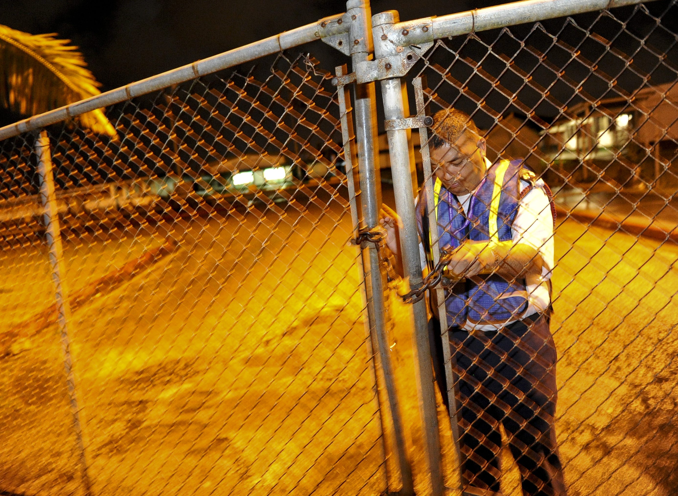 A G4S Jeff Toves uses a chain and padlock to secure the main gate to Maria A. Ulloa Elementary School in Dededo during the early morning hours of Dec. 27.