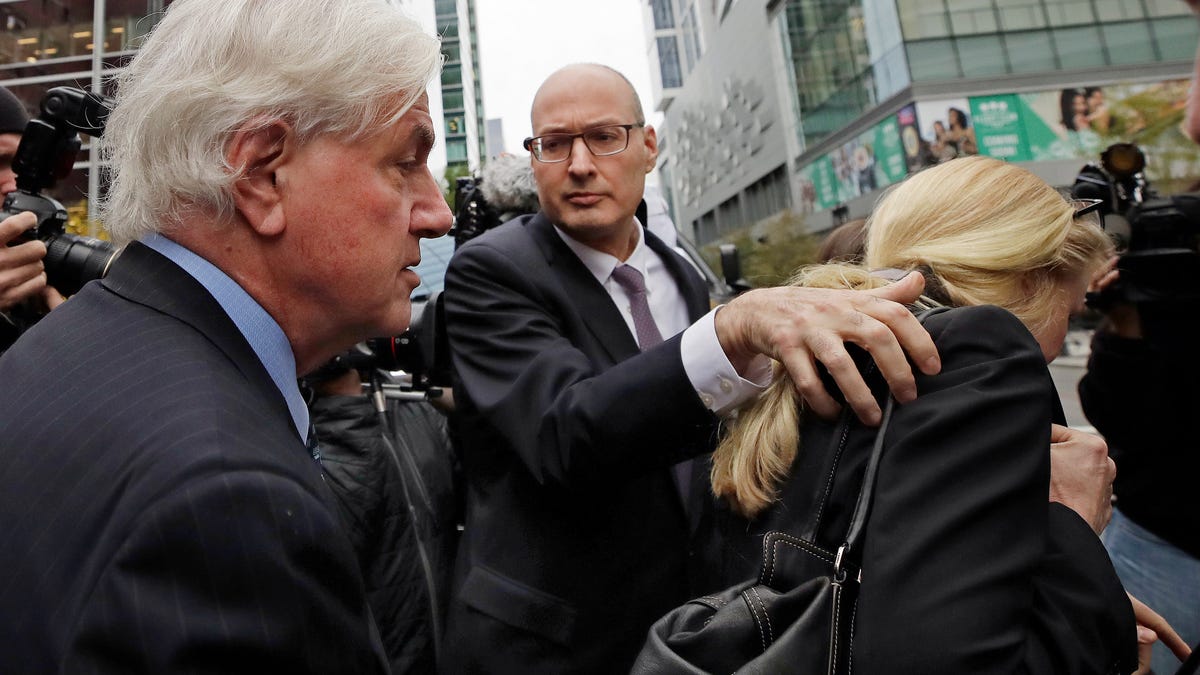 Gregory Abbott, far left, and his wife Marcia, far right, get into a car as they leave federal court after their sentencing in a nationwide college admissions bribery scandal, Tuesday, Oct. 8, 2019, in Boston.
