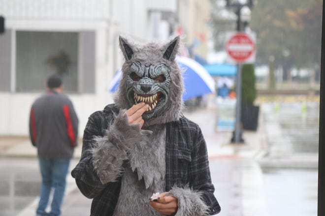 A werewolf roaming in downtown Port Clinton during the treat-or-treating on Saturday enjoys some candy along Madison Street.
