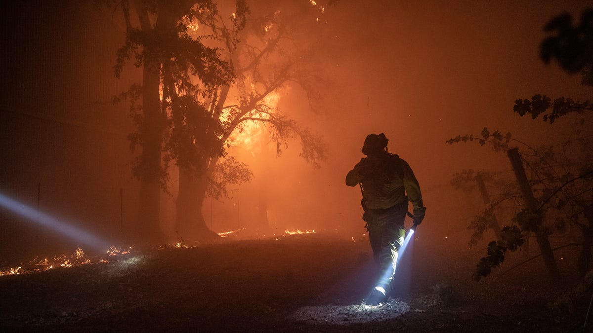 epa07953820 A firefighter walks pass a building burning out of control, as the Kincade Fire continues to burn in Healdsburg, California, USA, 27 October 2019.  According to reports, the Kincade Fire has burned more than 25,000 acres and triggered mandatory evacuations of about 90,000 residents in the area.  EPA-EFE/PETER DASILVA ORG XMIT: PDS01