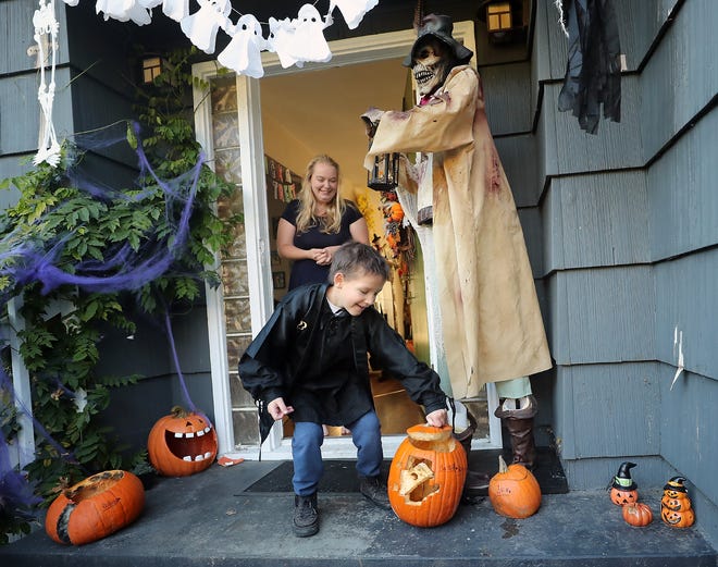 Azrael Early, 8, places the lid on his pumpkin as his mother, Jessie, looks on from the front door of their Bremerton home on Monday. Azrael's fight with cancer has made it difficult for him to fully participate in Halloween, but a special request will put him front-and-center for trick-or-treaters in downtown Bremerton this year.
