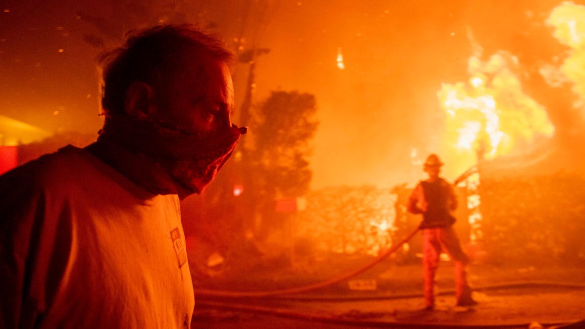 A man walks past a burning home during the Getty fire on Oct. 28, 2019, in Los Angeles.