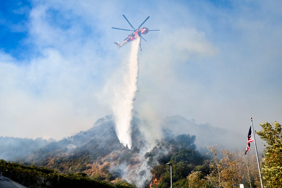 A helicopter drops water on the Gerry fire near the entrance of The Getty Center in Los Angeles.