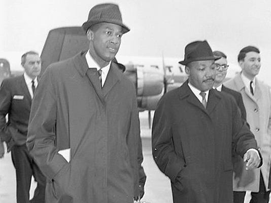 Dr. Martin Luther King Jr. arrives at the airport in Lansing on Feb. 11, 1965. He is accompanied here by MSU education professor Robert Green (left). King spoke to students at Michigan State University. Dr. Martin Luther King Jr. arrives at the airport in Lansing on Feb. 11, 1965. King spoke to students at Michigan State University.