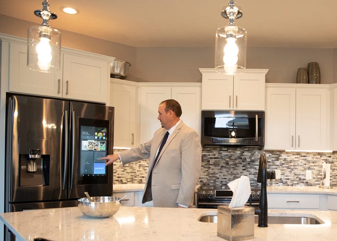 Courtyards at Deer Run developer Kevin Norman demonstrates a smart panel TV in a refrigerator that is one of the options available to residents who chose to live in the new customizable community.  