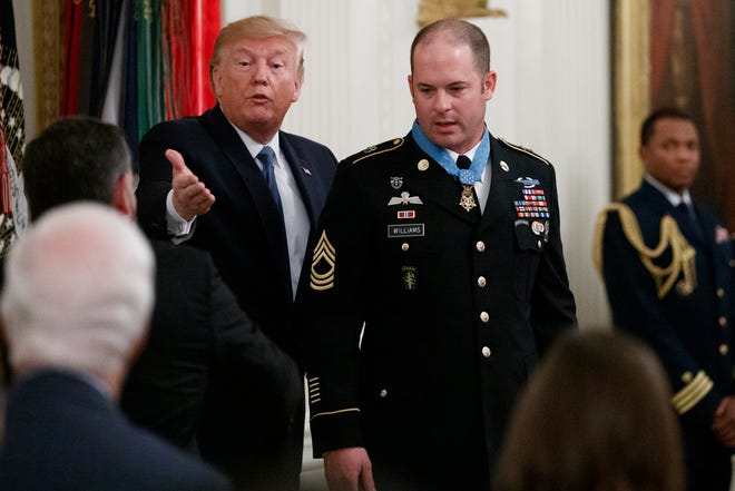 President Donald Trump gestures U.S. Army Master Sgt. Matthew Williams, currently assigned to the 3rd Special Forces Group, during a Medal of Honor Ceremony in the East Room of the White House, Wednesday, Oct. 30, 2019, in Washington.