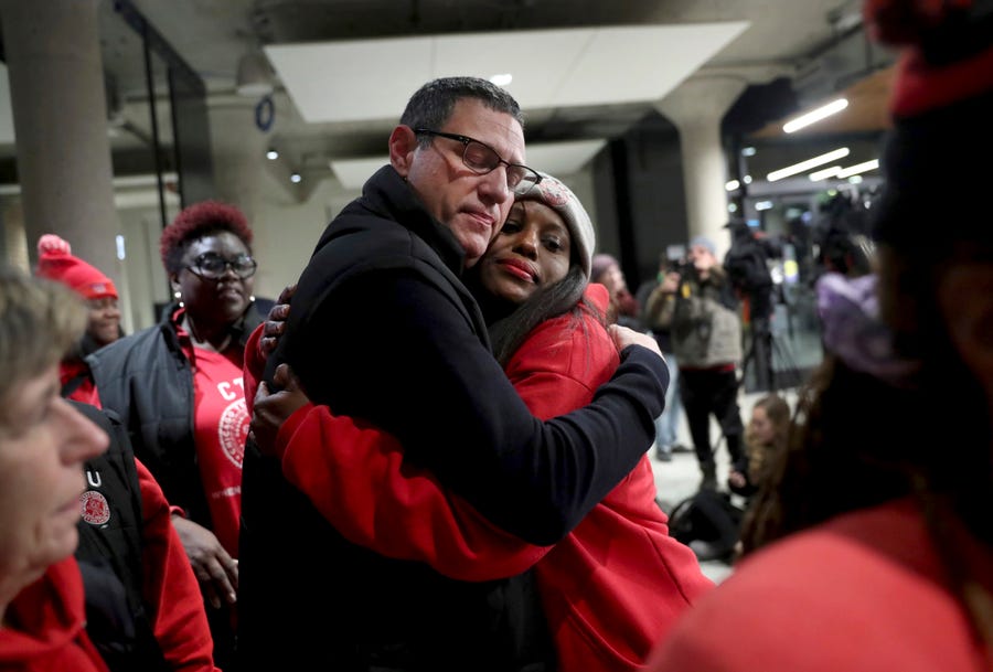 In this Wednesday, Oct. 30, 2019, Chicago Teachers Union President Jesse Sharkey and vice-president Stacy Davis Gates share a hug after speaking to the media following a CTU House of Delegates meeting at the Chicago Teachers Union Center in Chicago.  (Chris Sweda/Chicago Tribune via AP)