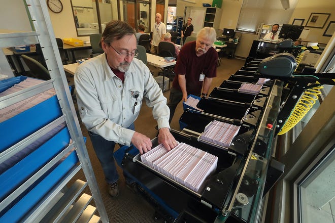 Election workers Harry Turnbull, left, and Rodney Kent place ballots into bins as a machine sorts them by precincts at the Kitsap County Auditor's Office on Tuesday.