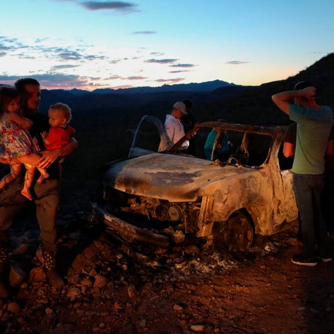 Members of the LeBaron family look at a burned car