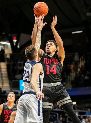 IUPUI Jaguars guard Marcus Burk (14) shoots the ball while being blocked by Butler Bulldogs forward Sean McDermott (22), Wednesday, Nov. 6, 2019, at Hinkle Fieldhouse, Indianapolis.  