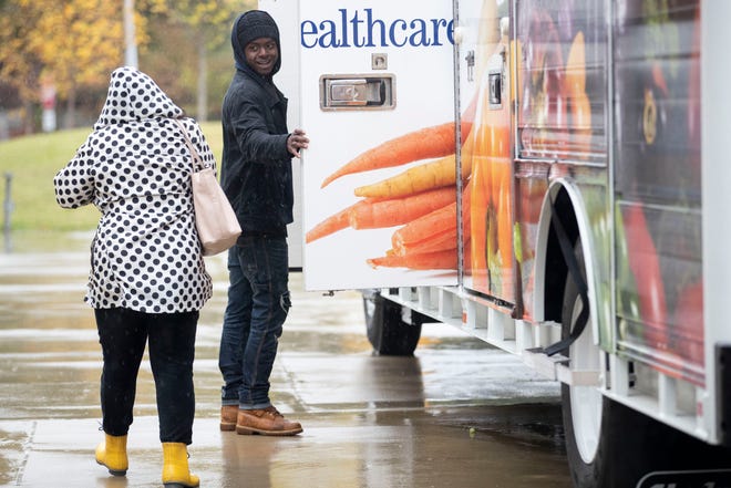 Mid-South Food Bank employee Ramico Brown, right, greets a woman as she arrives to get a bag of produce Thursday, Nov. 7, 2019, outside Crosstown Concourse in Memphis.
