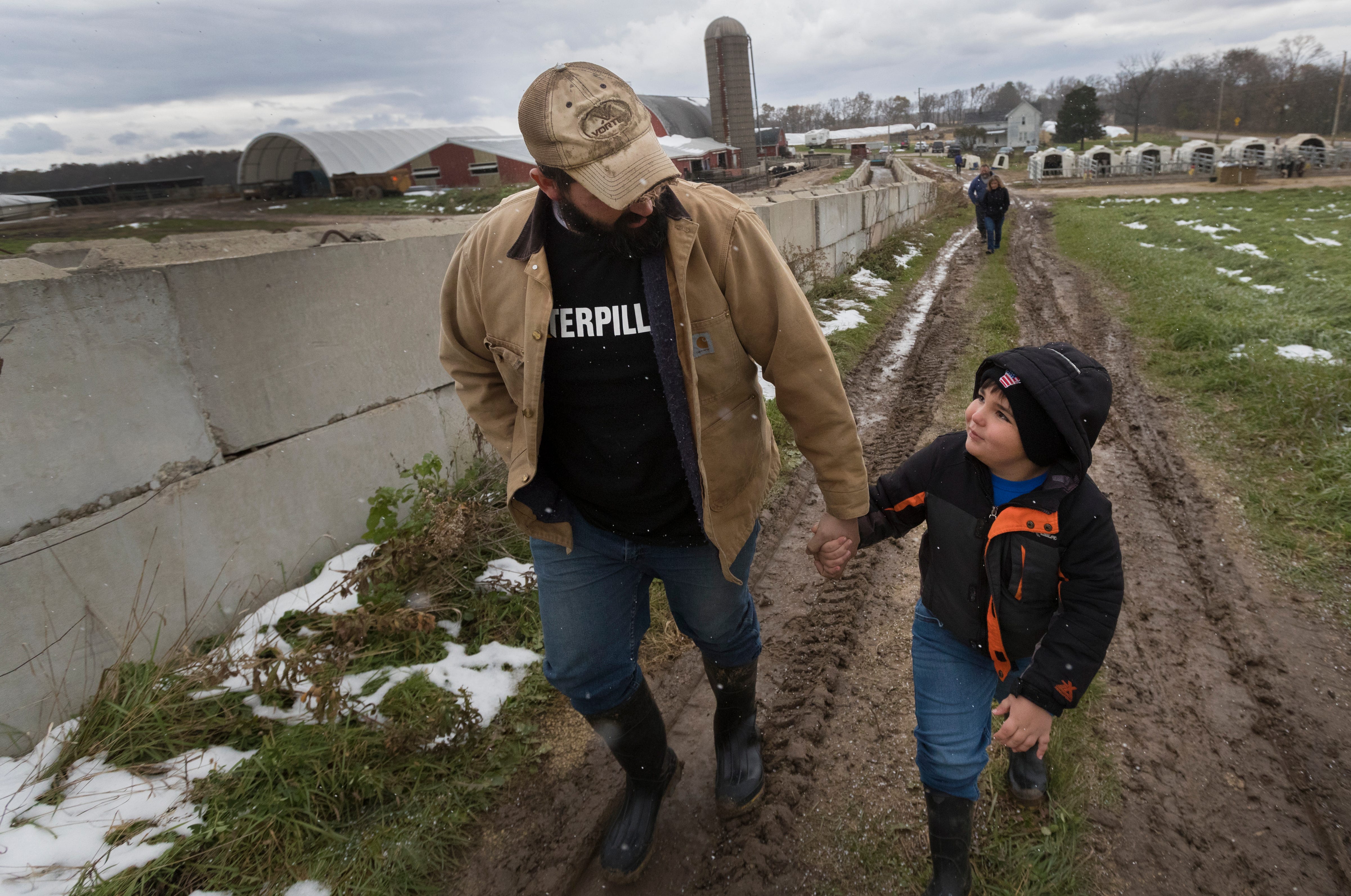 Tyler Gailloreto walks with his 6-year-old son, Leo, on their farm in Fort Atkinson.