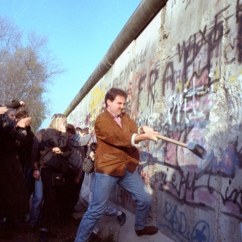An West Berliner swings a sledgehammer, trying to 