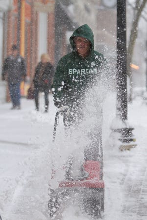 Mike Cleary, owner of Cleary's Pub in downtown Howell, clears the sidewalk in front of his establishment Monday, Nov. 11, 2019 as snow continues to fall heavily.