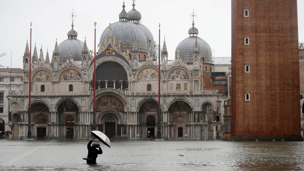 A photographer takes pictures in a flooded St. Mark's Square, in Venice, Italy, Tuesday, Nov. 12, 2019. The high tide reached a peak of just over four feet 10:35am while an even higher level of four and a half feet was predicted for later in the day. 