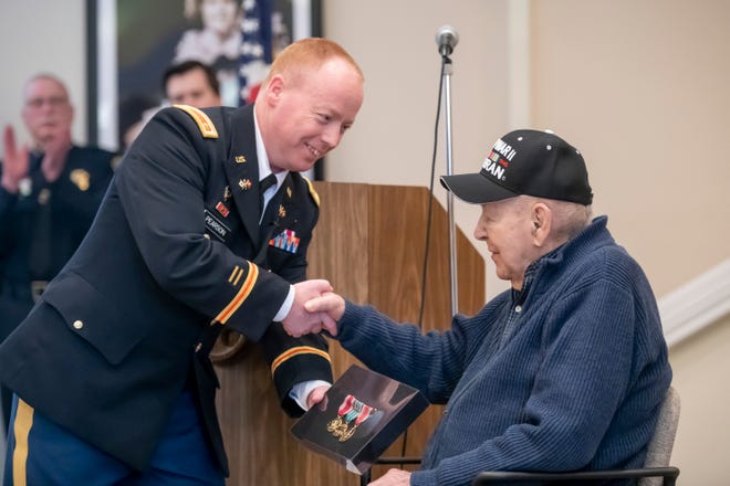 Major Daniel Pearson, Commander of the U.S. Army recruiting company in Dearborn, left, presents Army veteran Henry Kroll with three medals from his time in World War II.