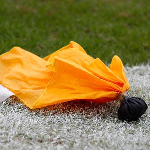 A penalty flag lies on the field during a college 
