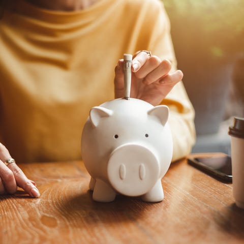 woman hand putting money bank note dollar into pig