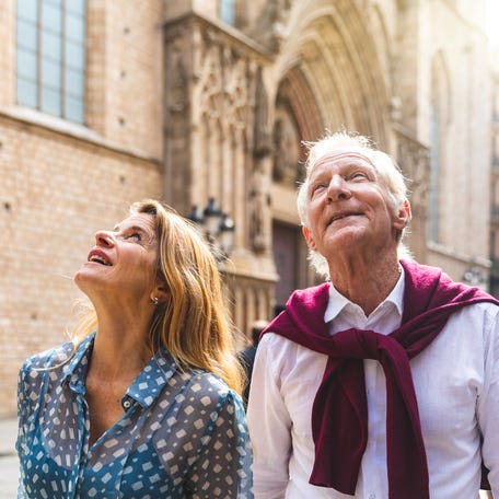 Senior couple of tourists visiting the old town in Barcelona. Adult woman and man looking up at some beautiful architecture on a sunny day in Spain. Travel and tourism concepts