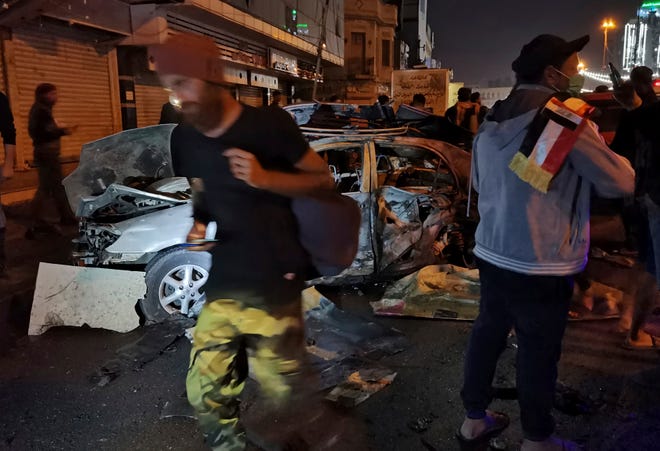 Anti-government protesters gather at the site of a bomb attack near Tahrir square in Baghdad, Iraq, Friday, Nov. 15, 2019. A bomb placed under a car exploded near the epicenter of anti-government protests in the capital, killed and wounded protesters, police and hospital officials said.