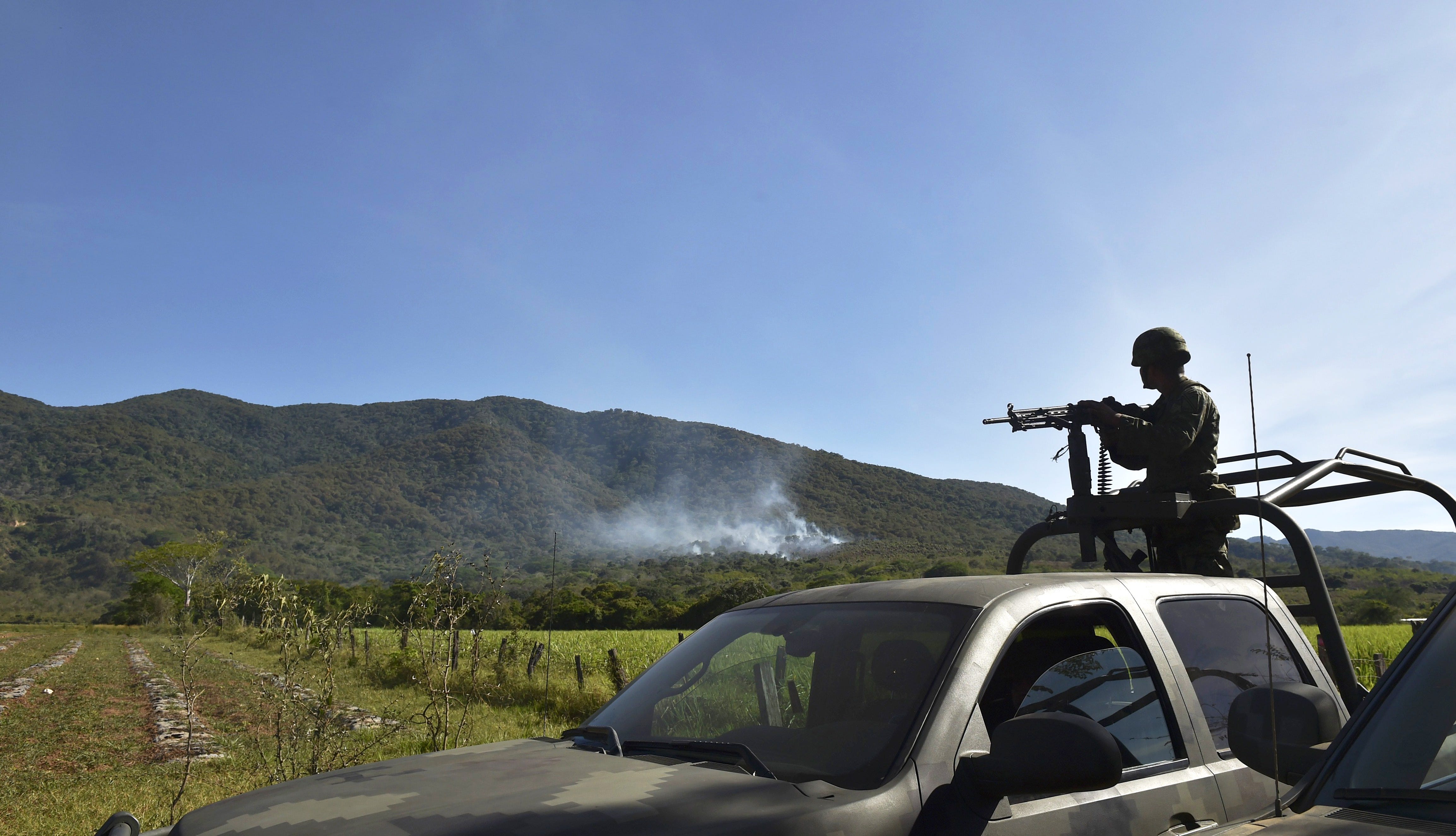 A Mexican soldier keeps an eye out for cartel members after CJNG downed a military helicopter with a grenade in Villa Purificacion, Jalisco. The deadly 2015 attack was part of escalating violence during CJNG's power grab.