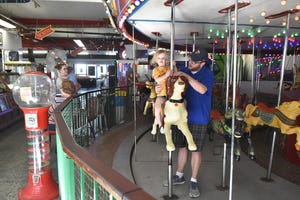 Harriet Overton rides the carousel in November 2019 at Ventura Harbor Village with the help of her dad, Daniel. The Village Carousel & Arcade will be open to the public for until Sunday.