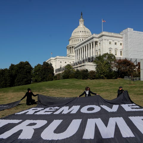 Demonstrators kneel near large banners on the lawn