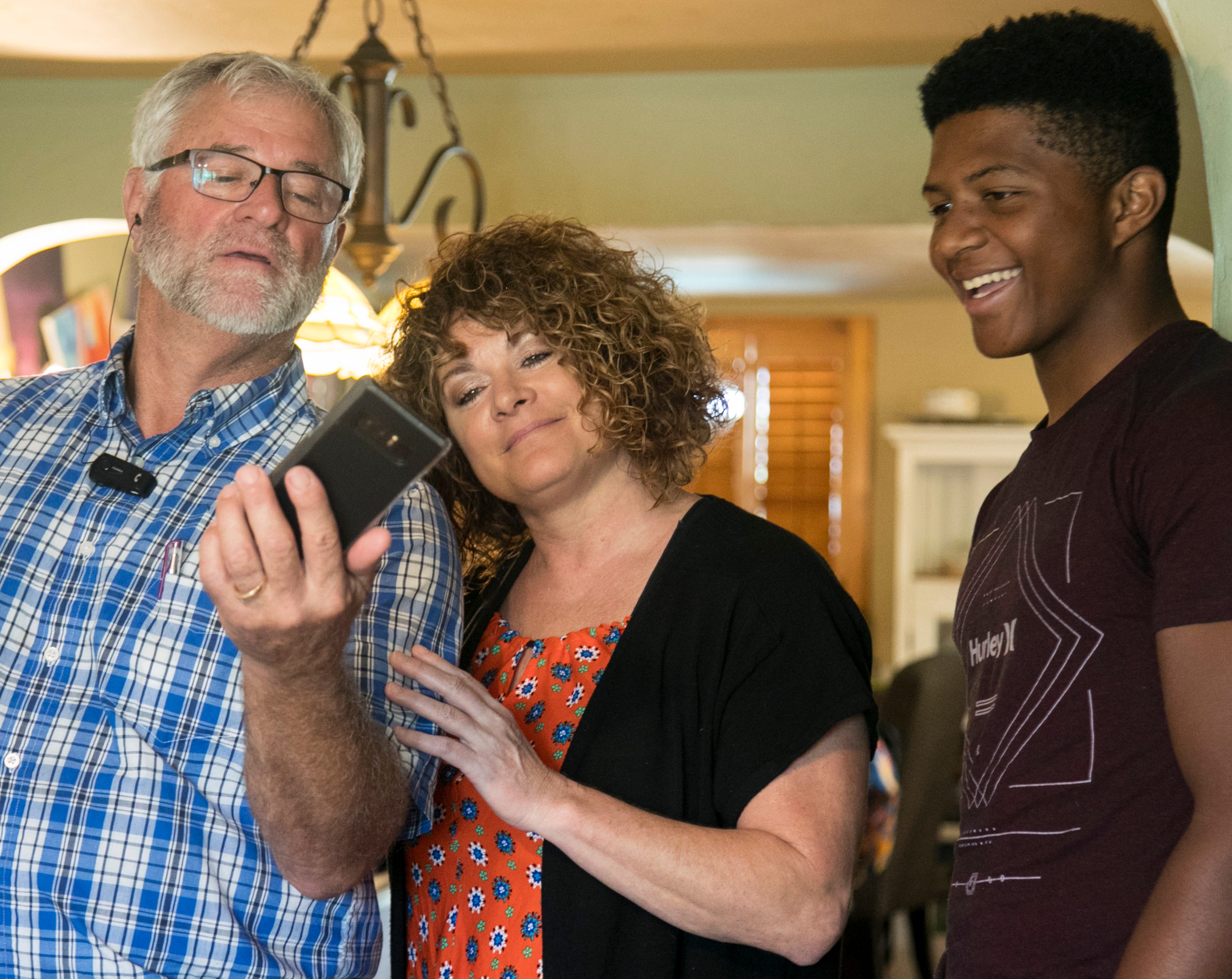 Anber's brother, Antonio Jr. (Tony), right, looks at old photos with his foster parents, Karen and Bruce Scott, at their North Fort Myers home in November 2018.