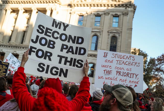 Teachers and protesters hold signs during the Red for Ed Action Day rally at the Indiana Statehouse in Indianapolis, Tuesday, Nov. 19, 2019.