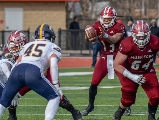 Muskegon's standout quarterback Cameron Martinez (13) handles a hike from center against DeWitt Saturday, Nov. 23, 2019. Muskegon won in a close game 28-21 to advance.