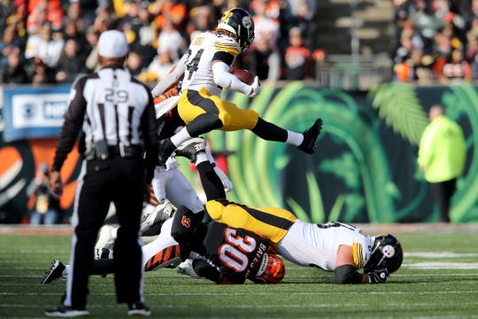 Pittsburgh Steelers running back Benny Snell (24) hurdles Cincinnati Bengals free safety Jessie Bates (30) on a run in the second quarter of an NFL Week 12 game, Sunday, Nov. 24, 2019, at Paul Brown Stadium in Cincinnati. 
