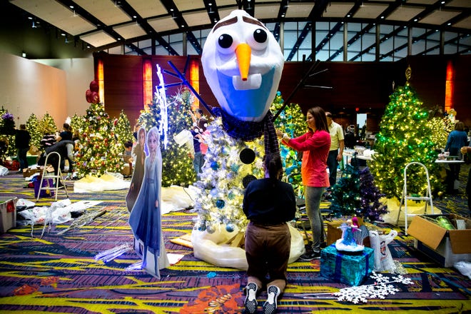Voluntários decoram árvores em preparação para o Festival de Árvores e Luzes no Centro de Eventos de Iowa.