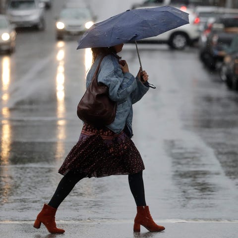A woman carries an umbrella while walking in the r