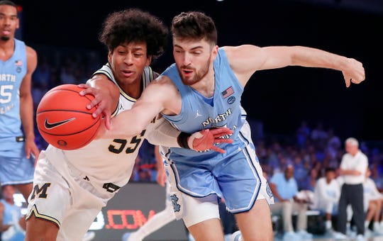 Michigan guard Eli Brooks and North Carolina guard Andrew Platek go for a loose ball during the first half in the Bahamas, Nov. 28, 2019.
