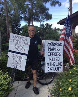 Bob Votruba is pictured with his bike and signs honoring fallen Naples Police Department officers.
