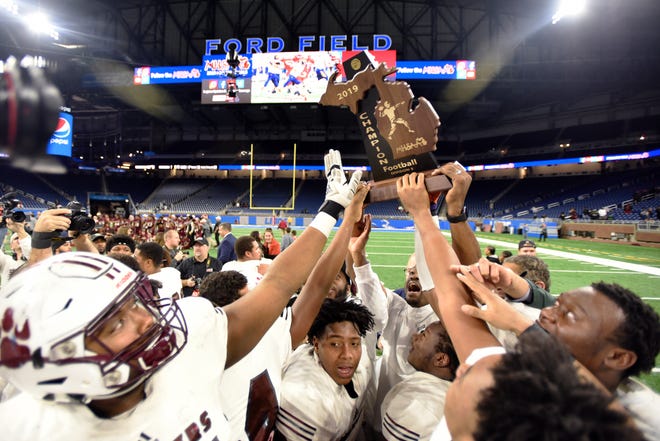 The River Rouge football team hoists the Division 3 trophy after defeating Muskegon 30-17 to win the state title in 2019.