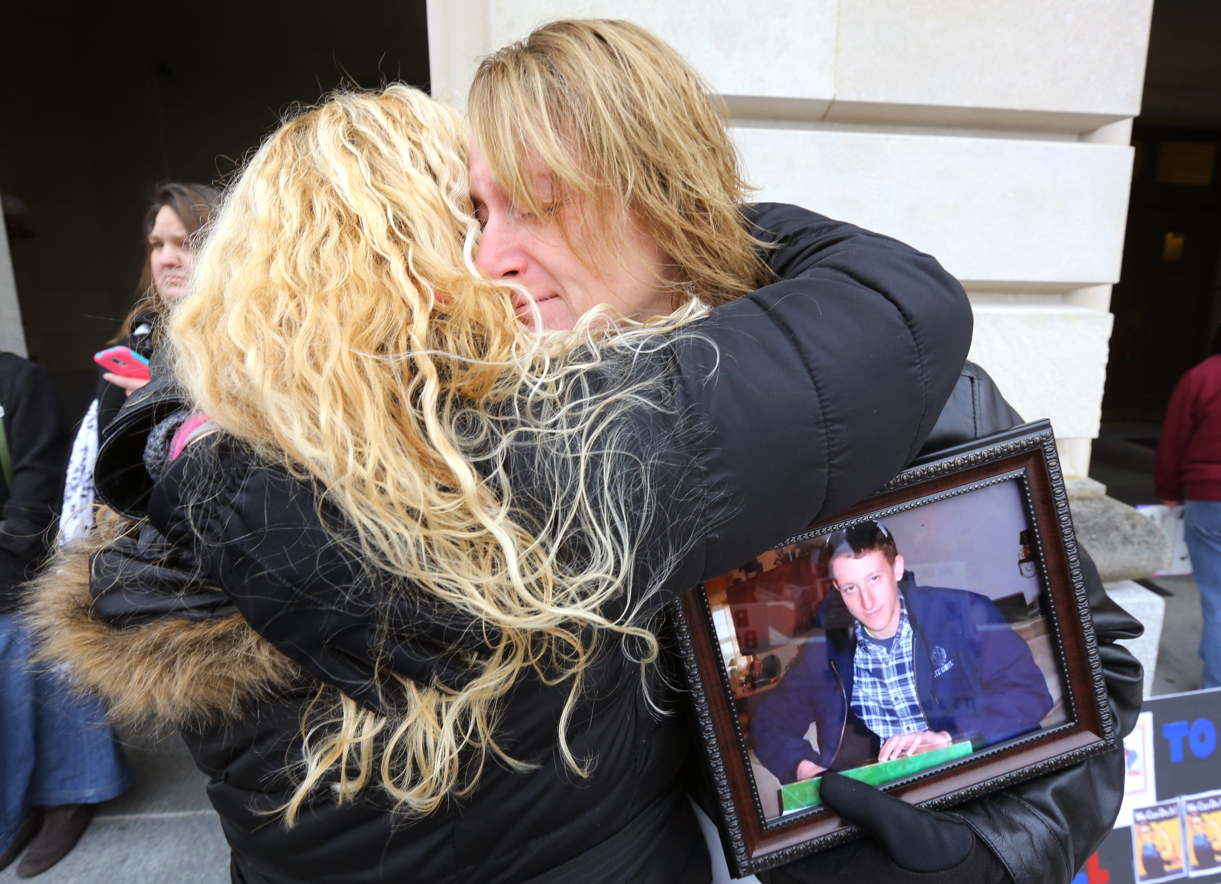 Rhonda Dupuy of Dry Ridge (right) accepts a hug from Pennie Tacket of Taylor Mill just months after Coty Glass, Rhonda's son (in photograph she holds) died from an overdose.
