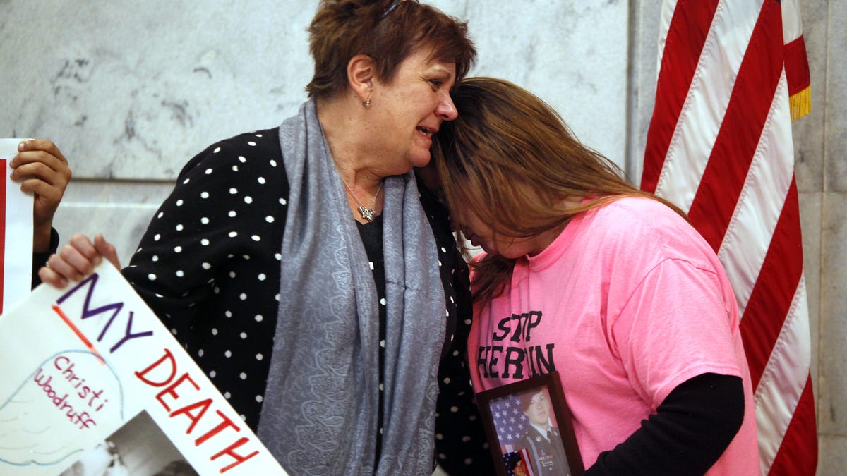 Jenni Woodruff (left), weeps as she clutches a poster with her daughter Christi's photograph. This was in Frankfort, Kentucky, where she was trying to convince legislators to approve needle exchange.