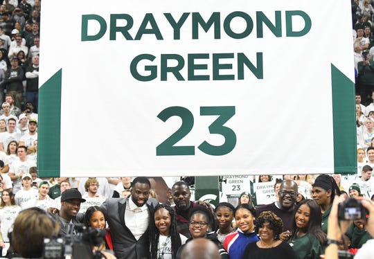 Former Michigan State basketball player Draymond Green and his family pose under his number during a halftime presentation retiring his number.