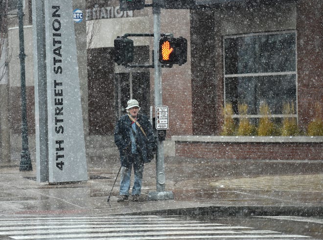 A file photo of a pedestrian crossing a crosswalk in snowfall.