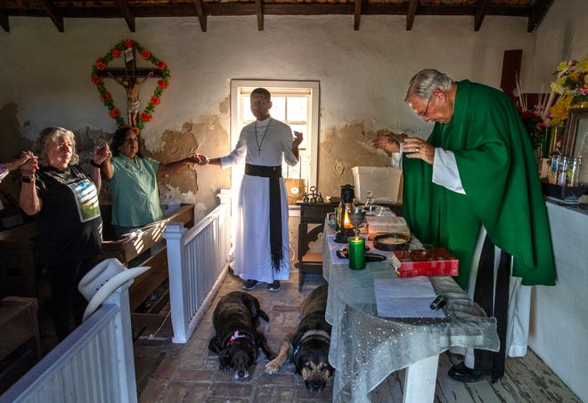 Father Roy Snipes says mass at La Lomita Chapel while his dogs, Charlotte, left and Bandito, right, lay on the brick floor. The chapel is at the center of a religious freedom lawsuit against the Federal government. The proposed border wall will cut off access to the site on the Rio Grande River. Sept. 17, 2019